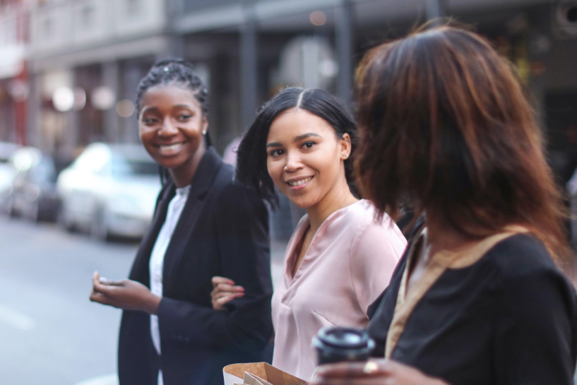 Three female friends walking in the street.